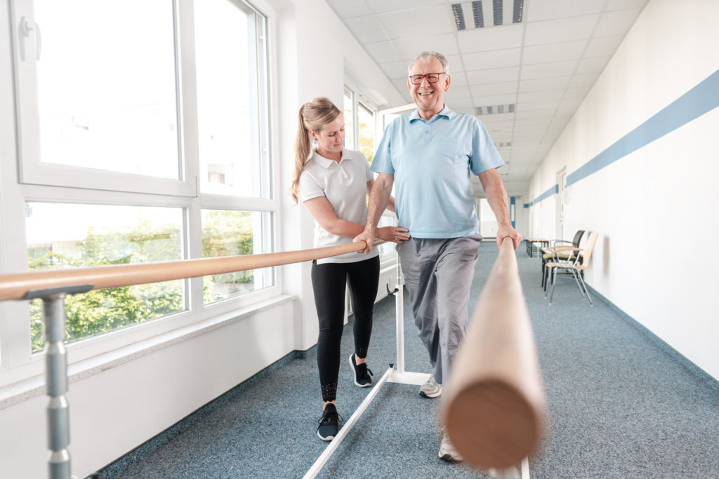 Senior Patient and physical therapist in rehabilitation walking exercises