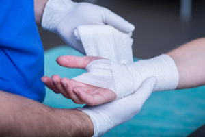 A man getting his hand bandaged after his hand surgery.