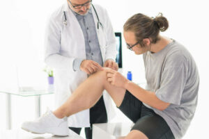 Full length of a young man getting his knee examined