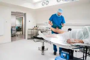 Surgeon wrapping elastic bandage on patient knee after surgery