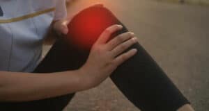 knee accident in sport exercise running jogging. low key lighting.