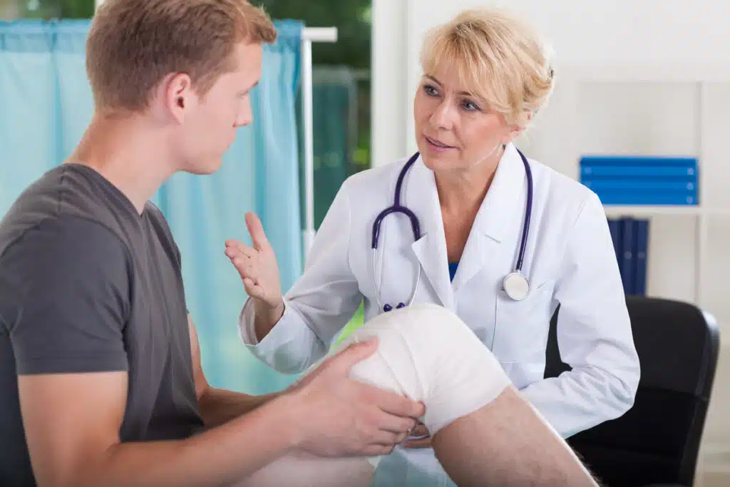 Doctor talking with patient after knee surgery
