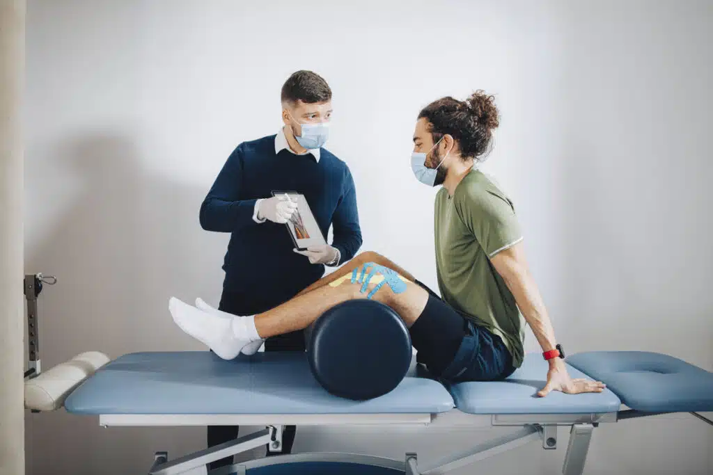 Sport Medicine Specialist Holding an Anatomy Chart and Explaining the Problem to the Patient