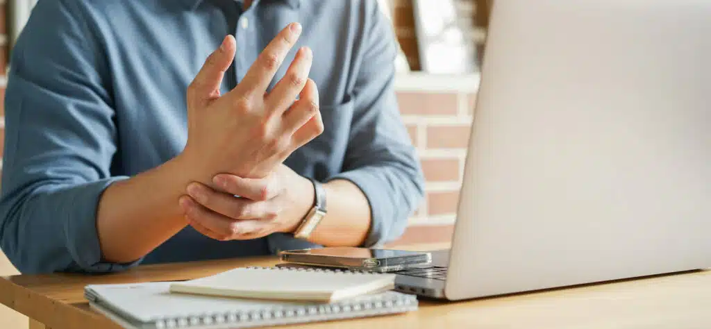 Close up of employee man holding wrist due to possible carpal tunnel syndrome.