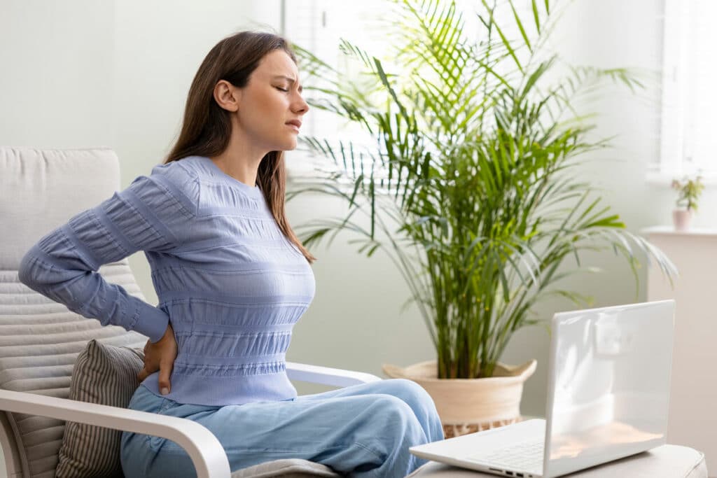 Young woman suffering with back pain at home.