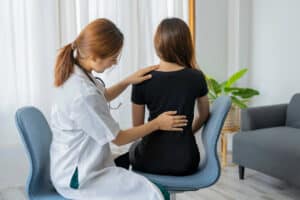 A female doctor is providing physiotherapy to treat her patients' back pain.
