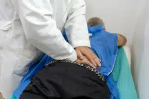 An orthopedic doctor is providing therapy and massage to a senior patient experiencing lower back pain.