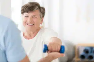 An elderly woman who specializes in osteoporosis is exercising with weights.