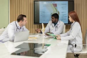 A group of knee replacement surgeons and radiologists discusses a patient's knee joint MRI and plans for further procedures.