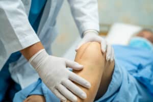 A surgeon examines the scar on a patient's knee after a knee surgery.