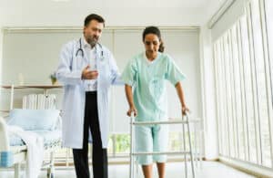 An orthopedic surgeon for hip replacement and a patient are in a hospital room.