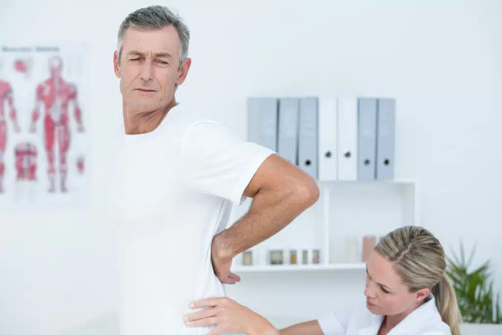 A female physiatrist for back pain is examining her patient back.